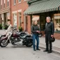 Two cruisers parked outside a small-town main street cafe at a mid-loop stop, riders holding their helmets